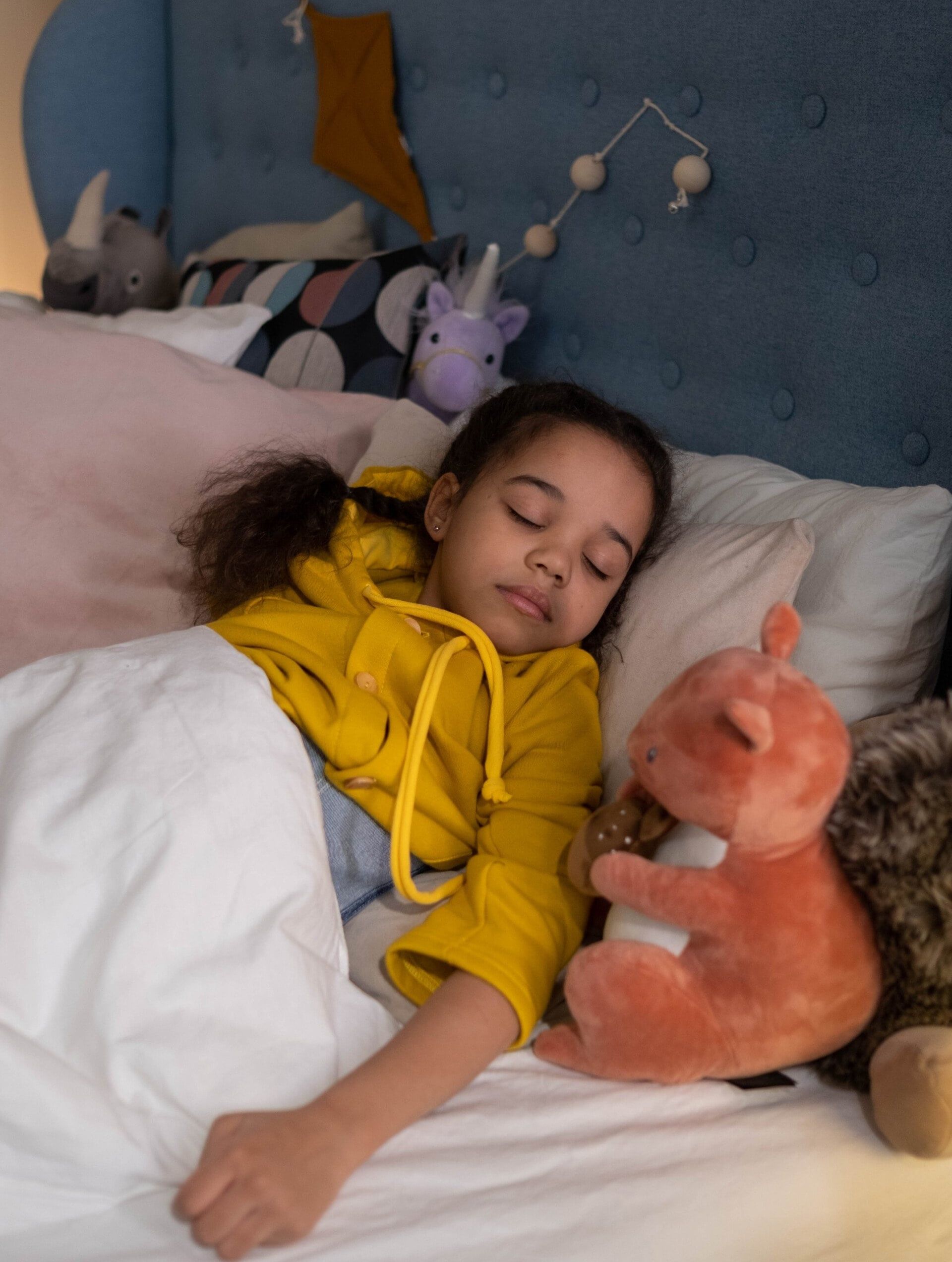 Child sleeping soundly in bed with soft toys after bed bug treatment
